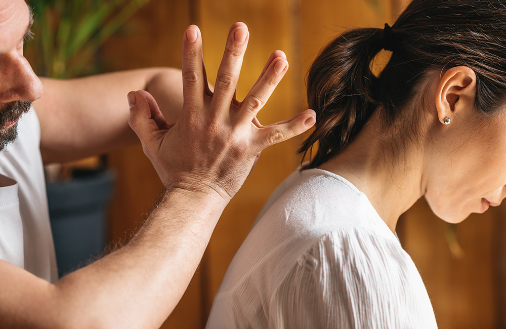 Masseur using Thai massage technique with hands to relieve neck and shoulders tension.